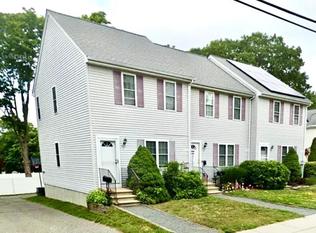 a view of a white house next to a yard