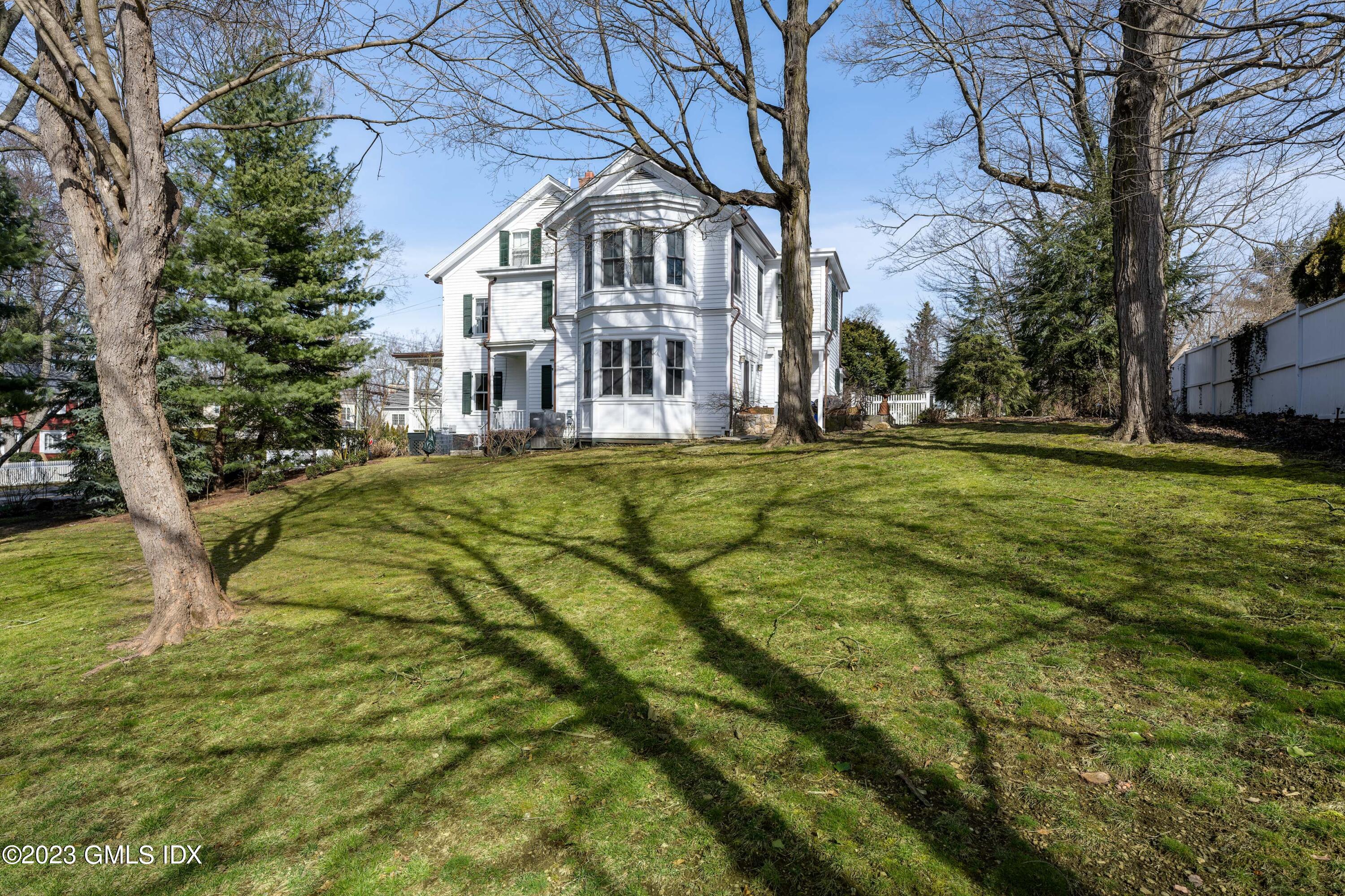 93 Riverside Avenue Riverside, CT 06878 - Photo 4 of 19 a view of a white house with a big yard and large trees