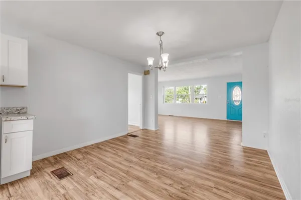 a view of an empty room with window and wooden floor