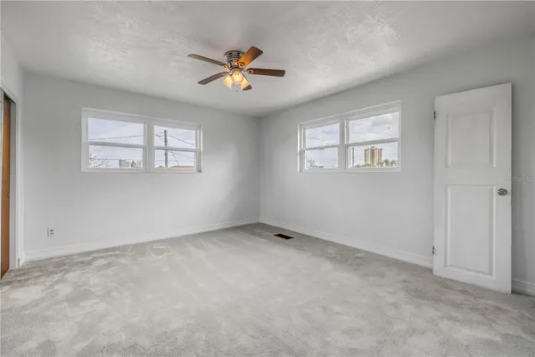 an empty room with windows and fan