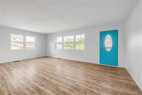 a view of an empty room with window and wooden floor