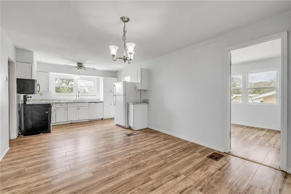 a view of a kitchen with refrigerator and wooden floor