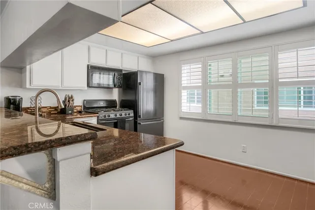 a kitchen with stainless steel appliances granite countertop a sink a stove and a refrigerator