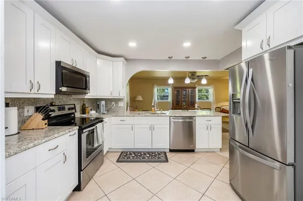 a large kitchen with a refrigerator a stove top oven a sink dishwasher and wooden cabinets