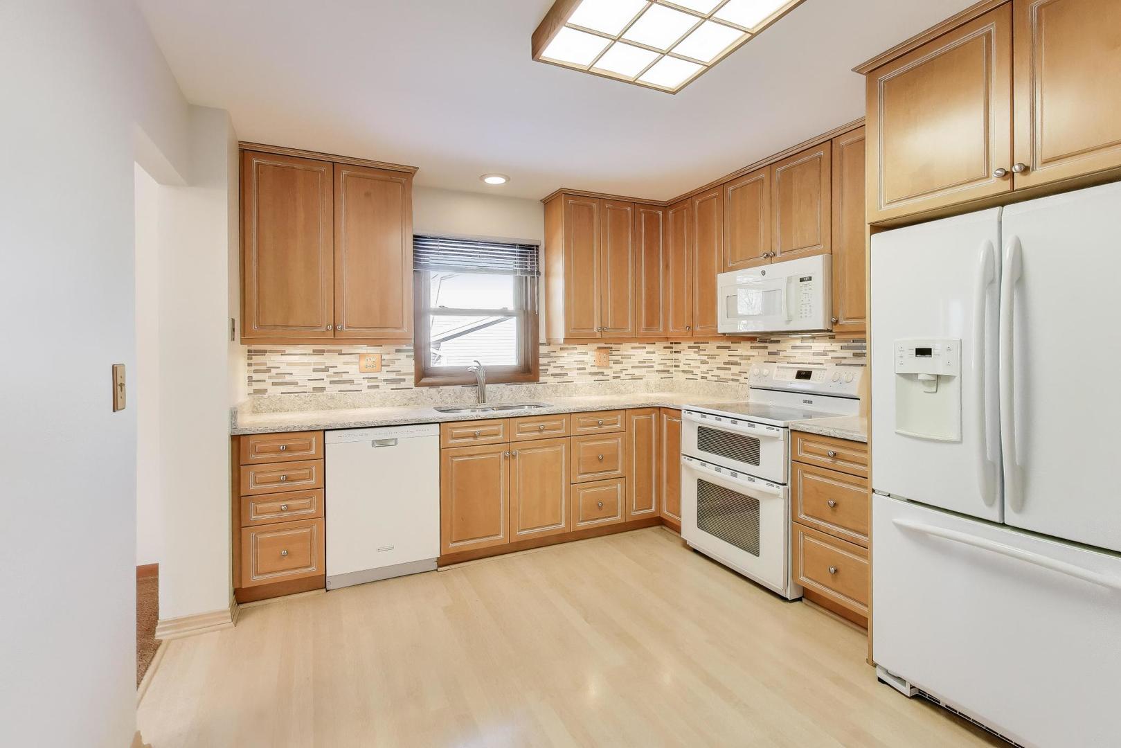 549 Ridgewood Lane Buffalo Grove, IL 60089 - Photo 7 of 17 a kitchen with stainless steel appliances white cabinets and wooden floors