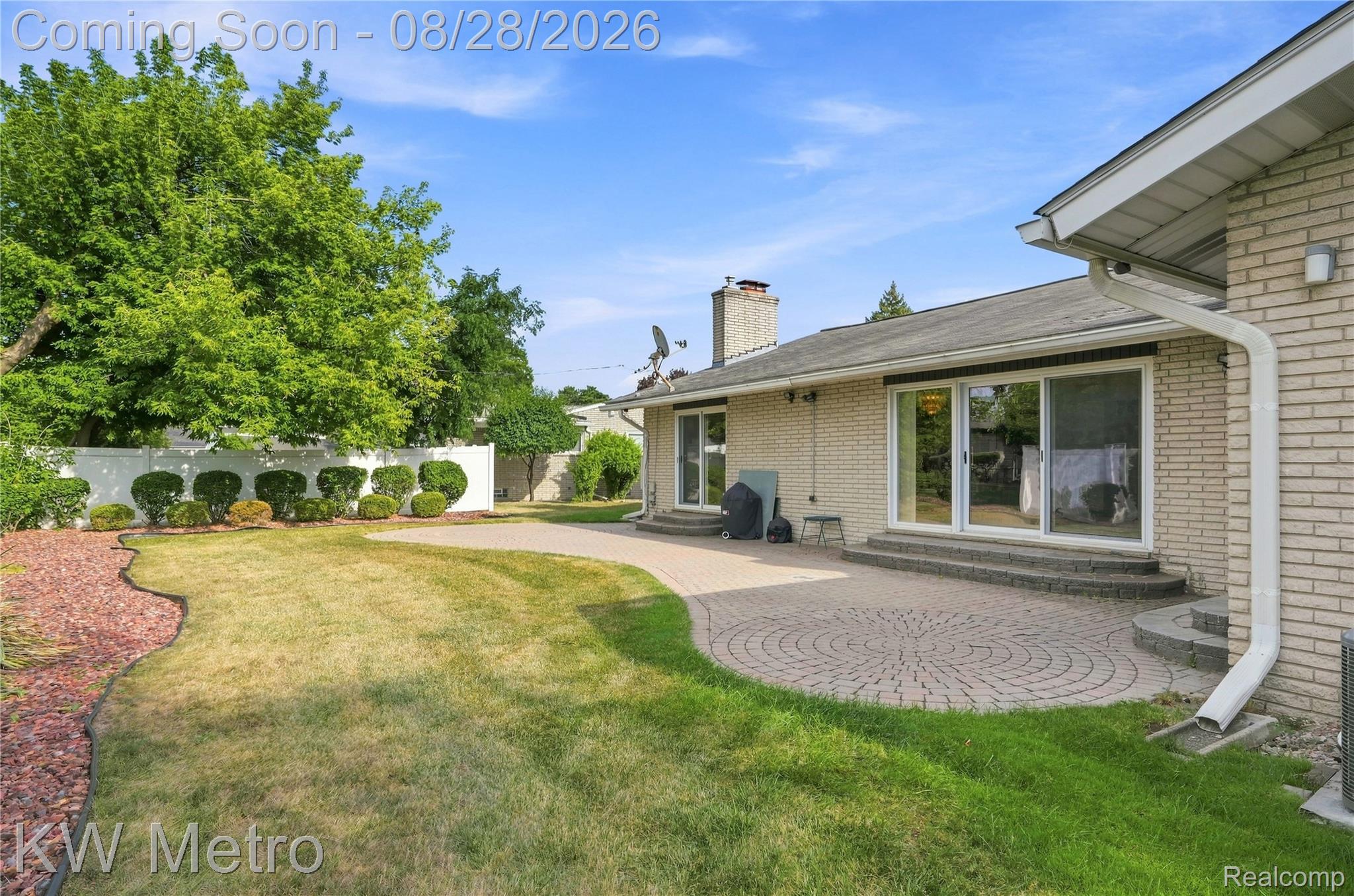 17700 Adrian Road Southfield, MI 48075 - Photo 18 of 24 Brick exterior with multiple sliding glass doors, a stone patio, and a privacy fence