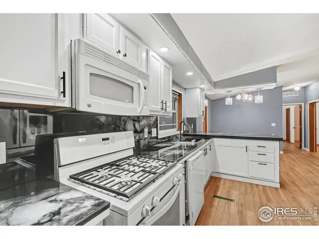 a kitchen with granite countertop a stove a sink and a microwave