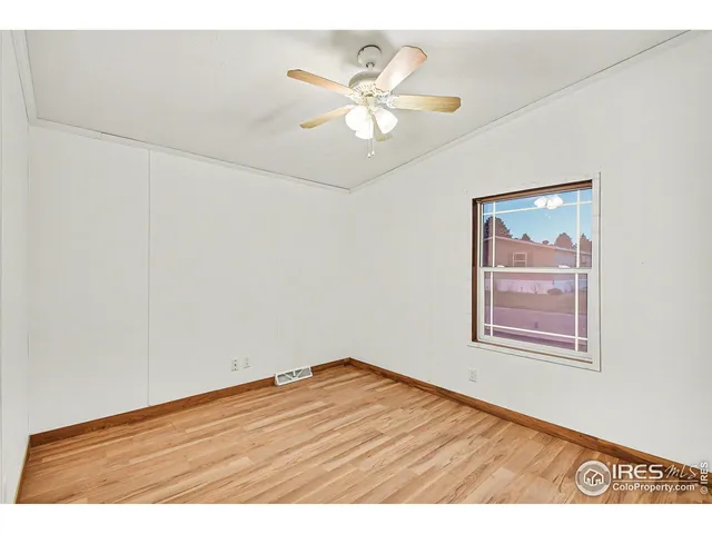 an empty room with wooden floor and ceiling fan