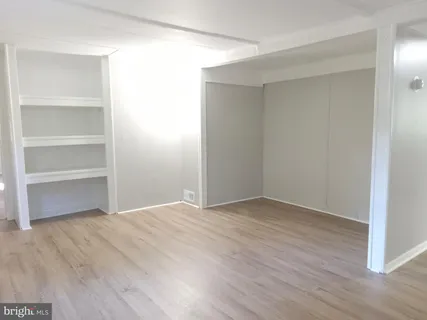 a view of an empty room with wooden floor and closet
