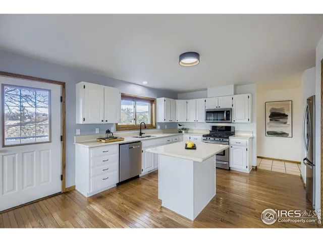 a kitchen with stainless steel appliances a sink a stove a refrigerator cabinets and a window