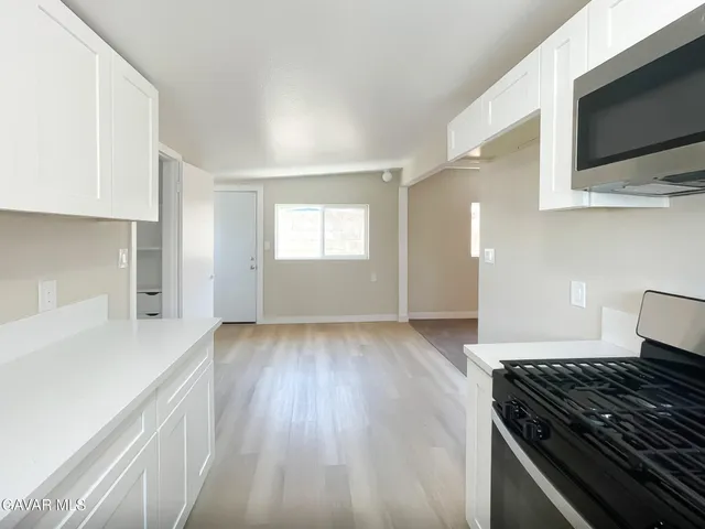 a kitchen with granite countertop a stove and a wooden floor