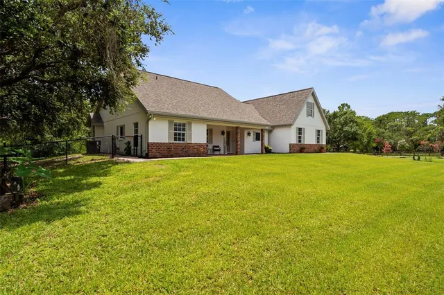 a view of house with a big yard and large trees