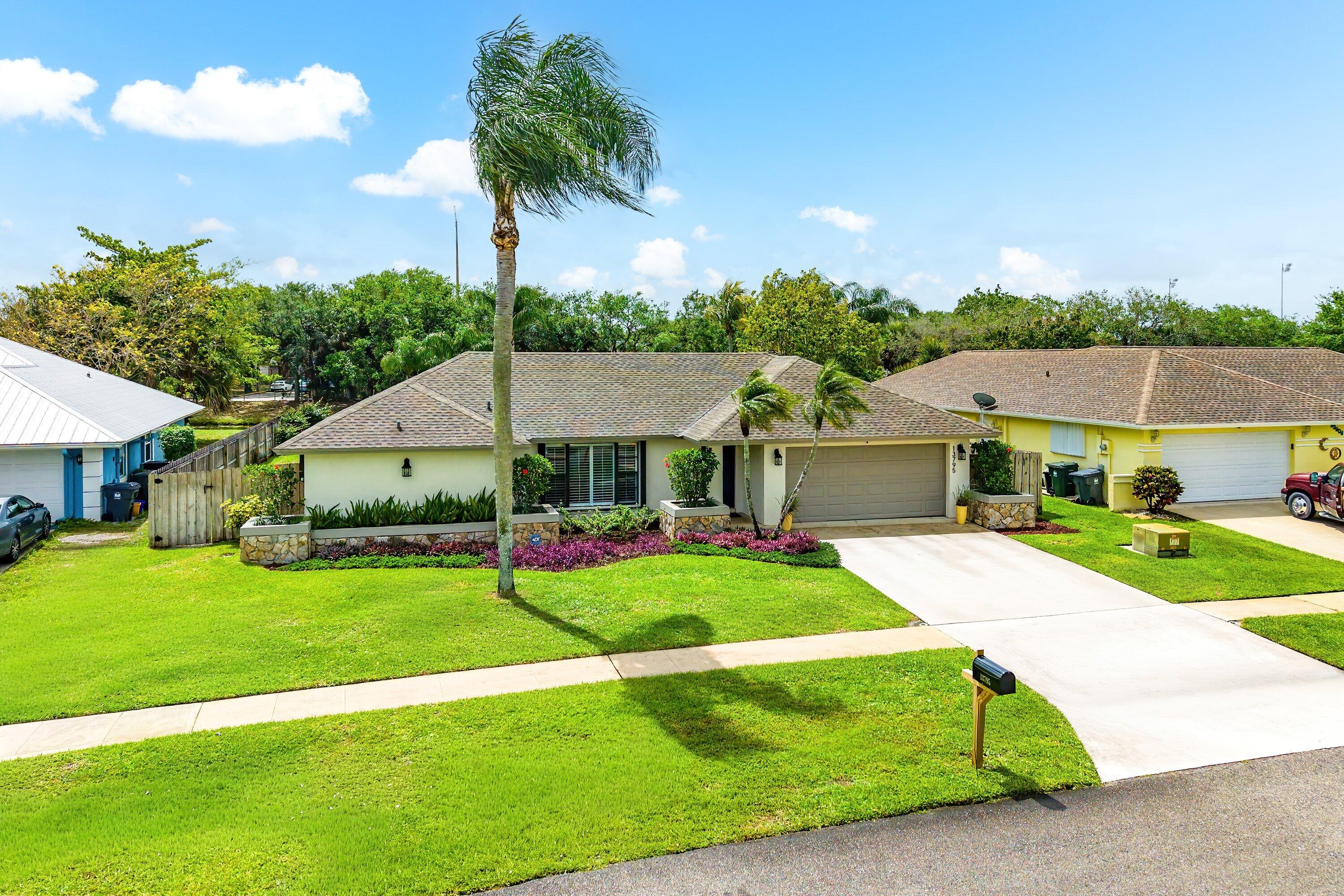 13795 Geranium Place Wellington, FL 33414 - Photo 30 of 37 a front view of a house with garden