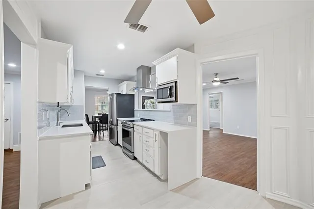 a kitchen with white cabinets and stainless steel appliances