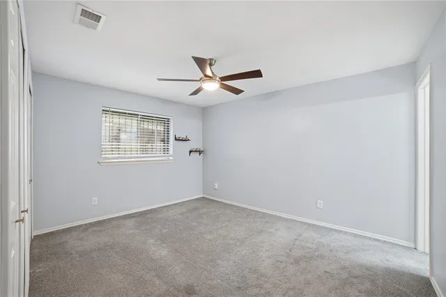 an empty room with a window and a fan