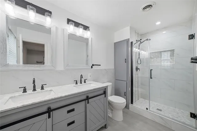 a bathroom with a double vanity sink toilet mirror and shower