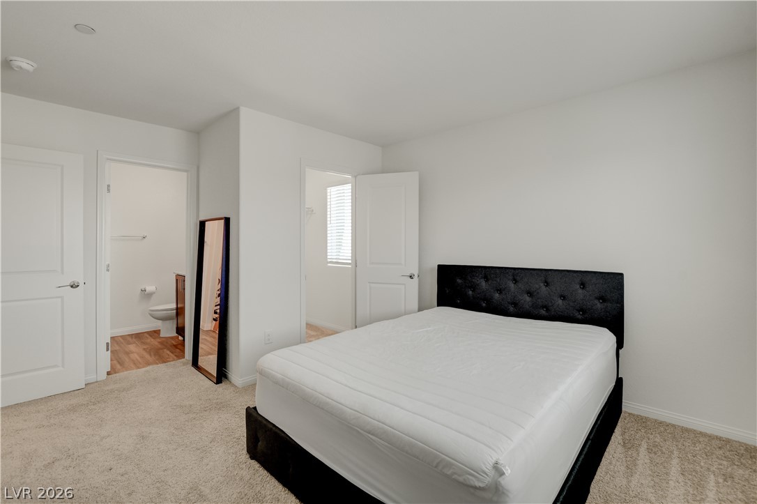 6924 Spicy Merlot Street North Las Vegas, NV 89086 - Photo 35 of 83 Plush carpeting defines this bright bedroom, offering serene comfort and seamless access to a private bathroom.