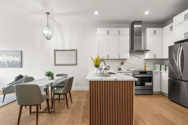 a kitchen with stainless steel appliances granite countertop a stove a refrigerator a kitchen island a dining table and chairs