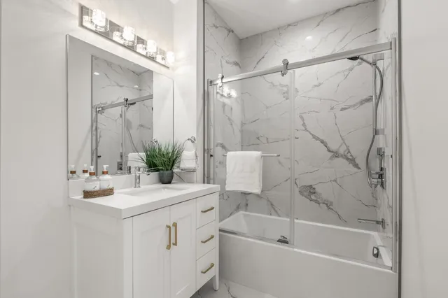 a bathroom with a bathtub a sink a large mirror and shower