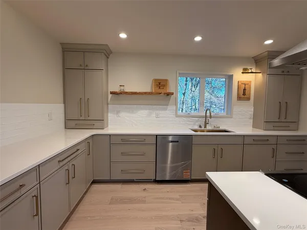 a kitchen with a sink dishwasher window and cabinets