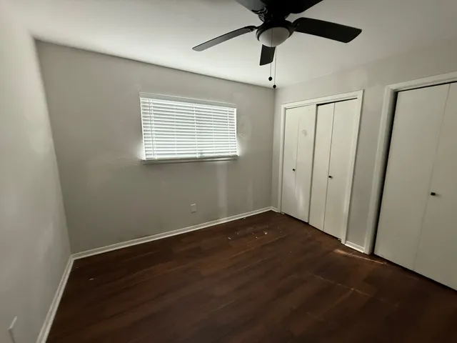 a view of a room with wooden floor and a ceiling fan