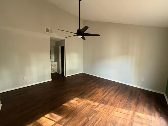 a view of an empty room with wooden floor and a window
