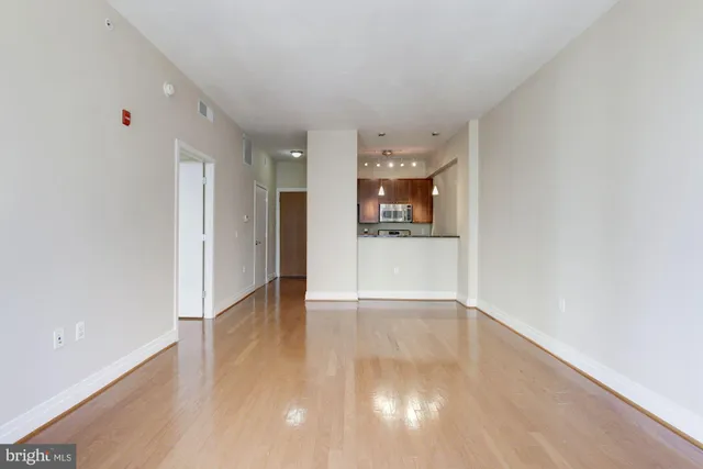 a view of a hallway with wooden floor and a refrigerator