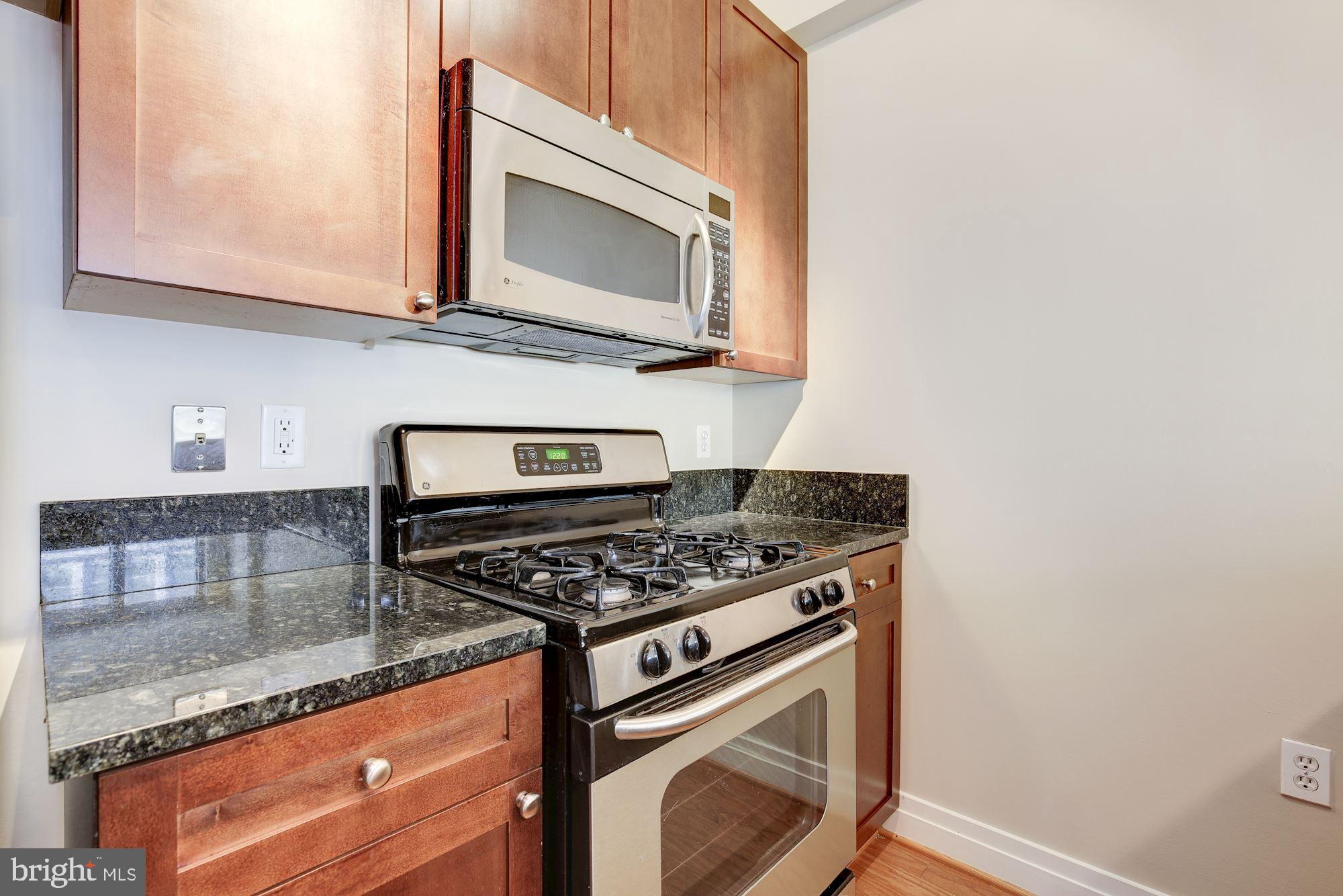 2120 Vermont Avenue Northwest, Unit 402 Washington, DC 20001 - Photo 15 of 41 a kitchen with granite countertop cabinets stove top oven and microwave