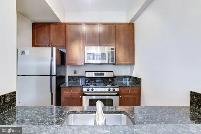 a kitchen with granite countertop a refrigerator stove and microwave