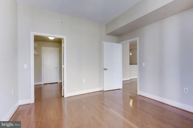 a view of an empty room with wooden floor and a bathroom