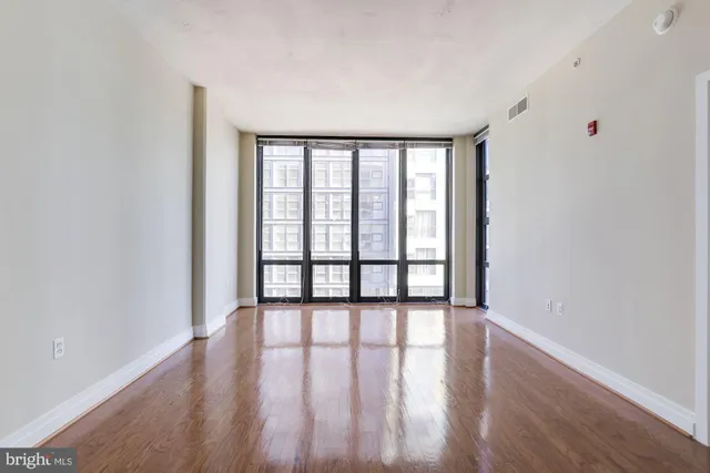 a view of an empty room with wooden floor and a window