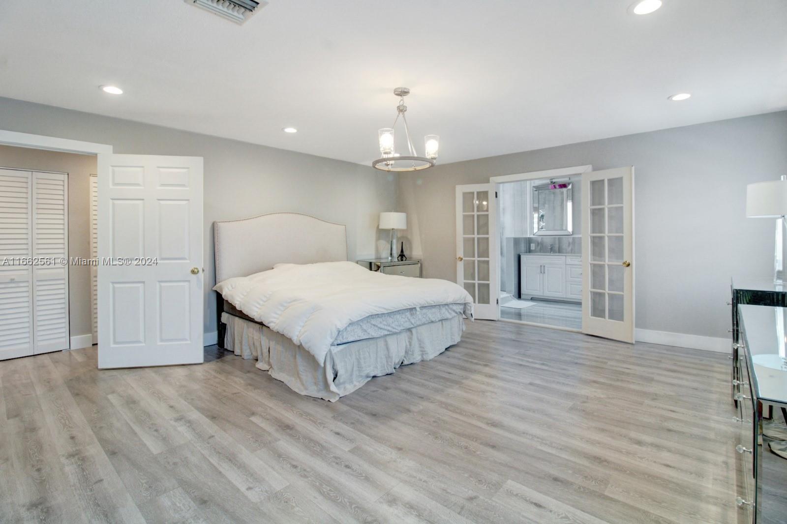 13505 Southwest 119th Street Miami, FL 33186 - Photo 12 of 25 a spacious bedroom with a large bed chandelier and a dresser