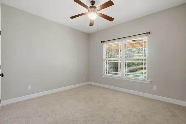 an empty room with a window and a ceiling fan
