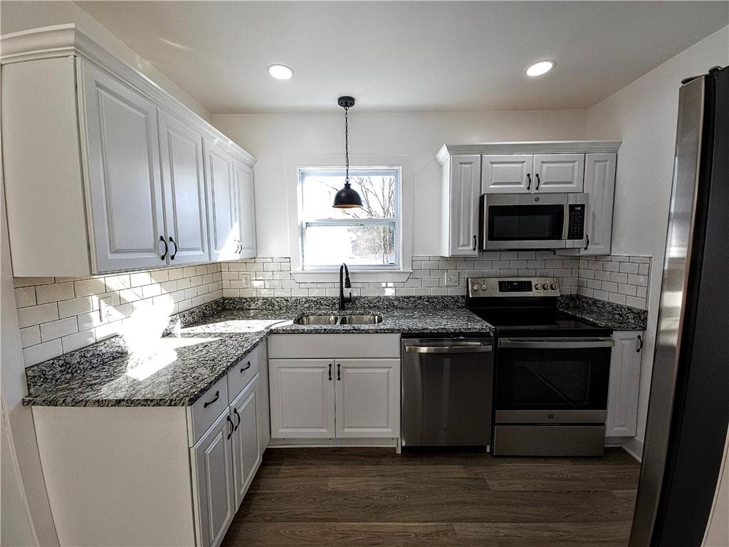 10200 Frankstown Road Pittsburgh, PA 15235 - Photo 21 of 47 a kitchen with stainless steel appliances granite countertop a stove top oven a sink dishwasher and a refrigerator with wooden floor