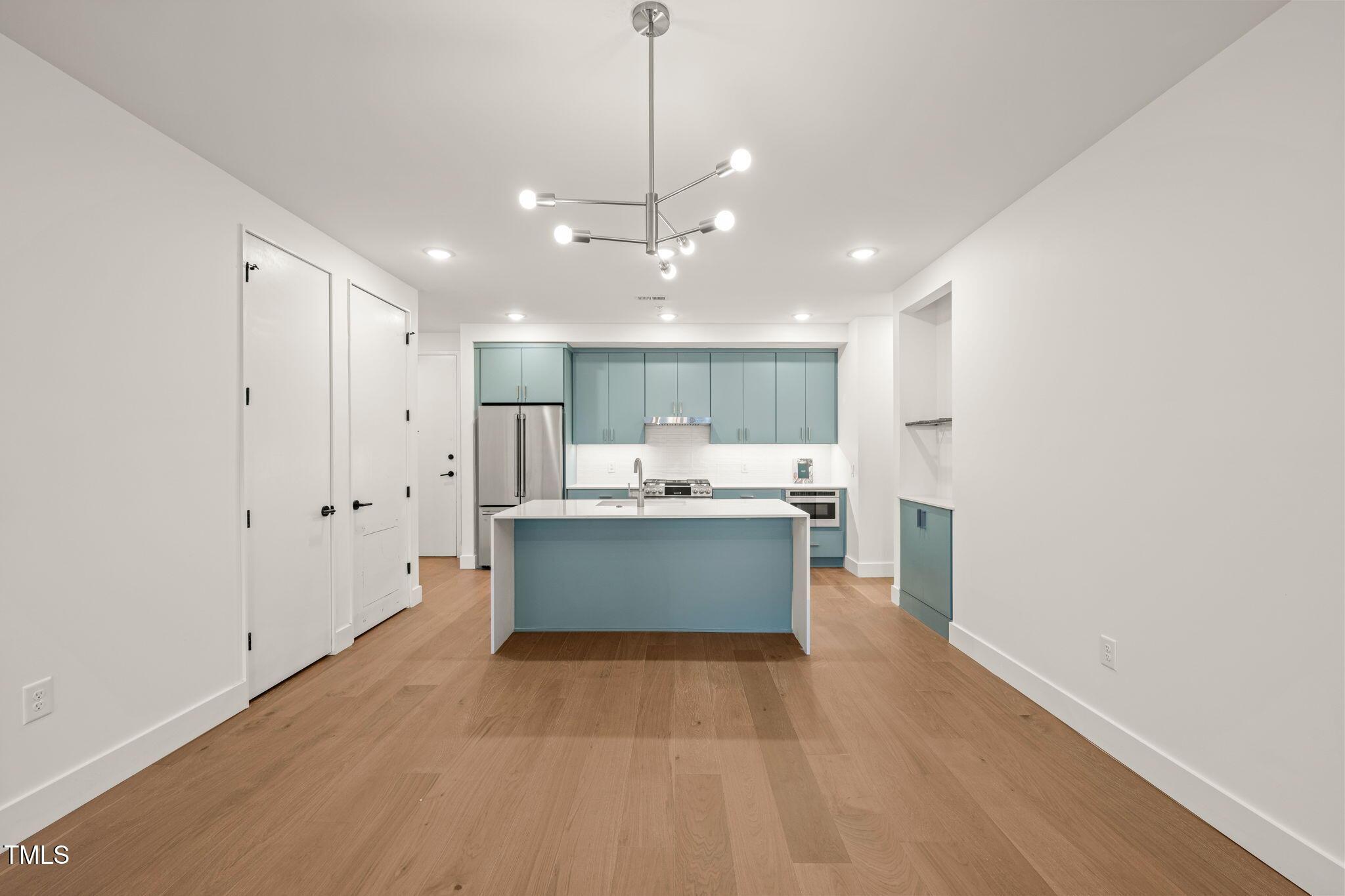 29 Enterprise Street, Unit 209 Raleigh, NC 27607 - Photo 3 of 46 a view of a kitchen with kitchen island a sink wooden floor and a refrigerator