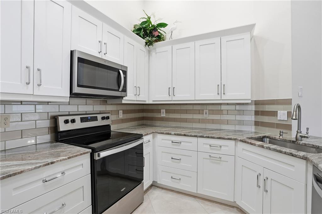 3724 Stone Way Estero, FL 33928 - Photo 15 of 35 Kitchen with stainless steel appliances, white cabinetry, light stone counters, and decorative backsplash