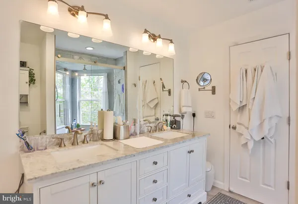 a bathroom with double vanity sinks a toilet a mirror and a shower