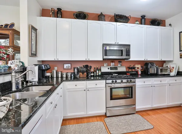 a kitchen with stainless steel appliances granite countertop a stove a sink and a microwave