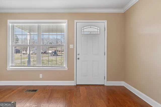 a view of an empty room with wooden floor and a window