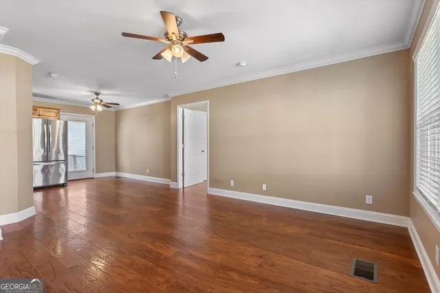 a view of an empty room with window and wooden floor