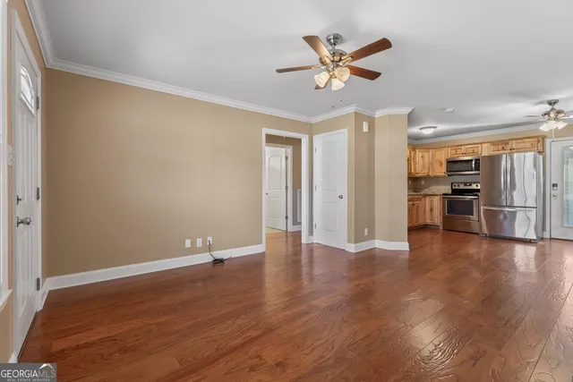 an empty room with wooden floor ceiling fan and a window