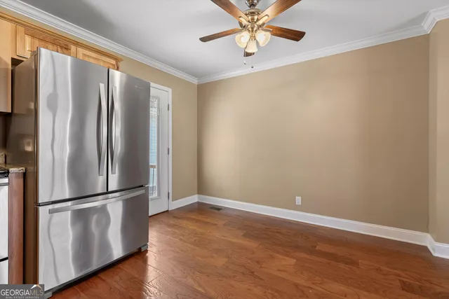 an empty room with wooden floor fan and windows