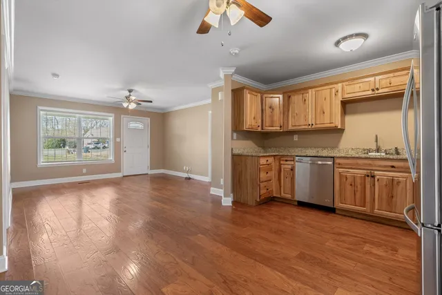 a kitchen with stainless steel appliances granite countertop a refrigerator a sink dishwasher a stove with white cabinets and wooden floor