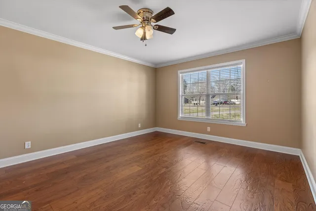 a view of an empty room with window and wooden floor