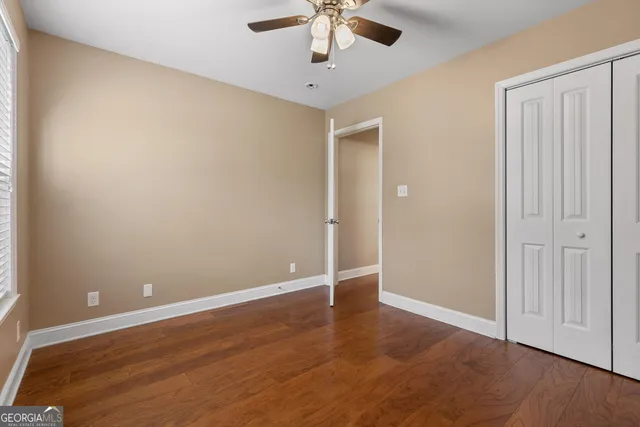 an empty room with wooden floor fan and windows