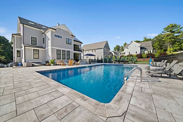 a view of swimming pool with outdoor seating and house in the background