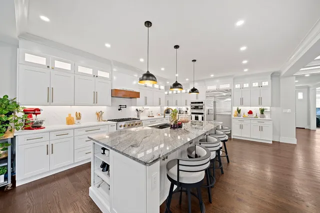 a kitchen with stainless steel appliances kitchen island granite countertop a stove a sink and a refrigerator