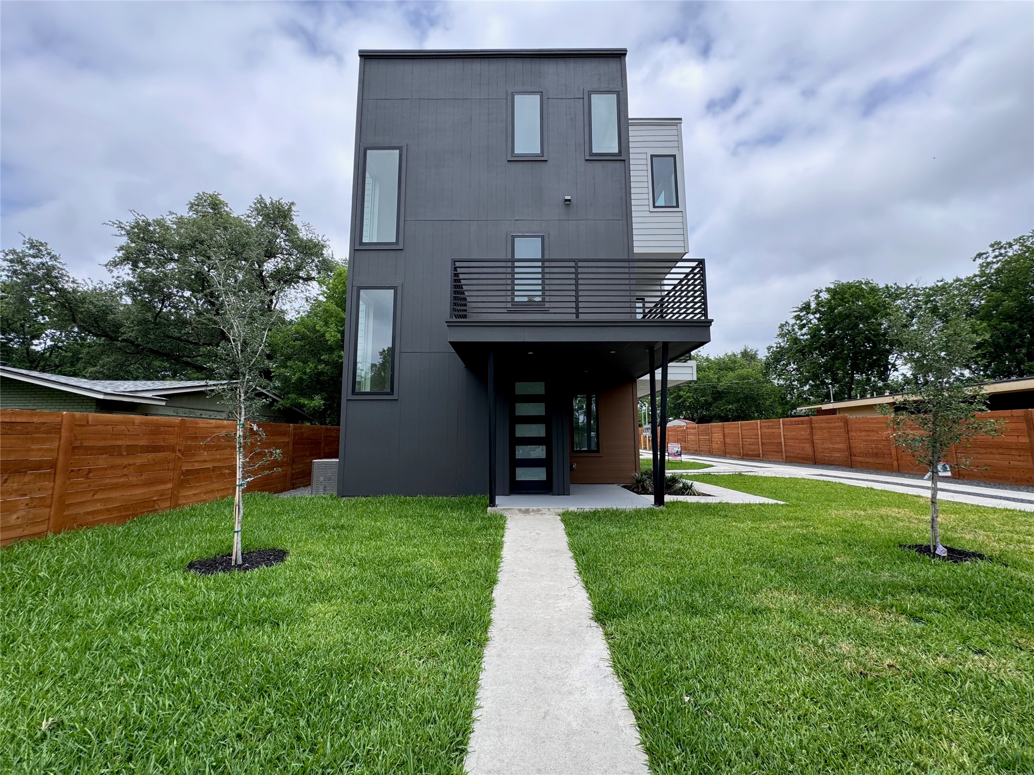 100 West Odell Street, Unit 1 Austin, TX 78752 - Photo 39 of 39 Modern architectural facade featuring dark paneling, a private balcony with black metal railing, and vertical window accents