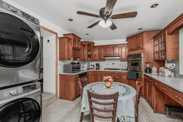 a kitchen with stainless steel appliances granite countertop a sink a stove a refrigerator cabinets and a dining table