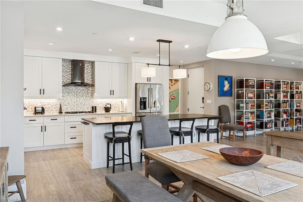 1135 3rd Avenue South, Unit 119 Naples, FL 34102 - Photo 13 of 50 a kitchen with stainless steel appliances kitchen island granite countertop a table chairs sink and cabinets